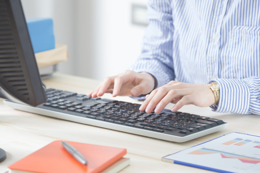 close up of computer keyboard with person's hands typing