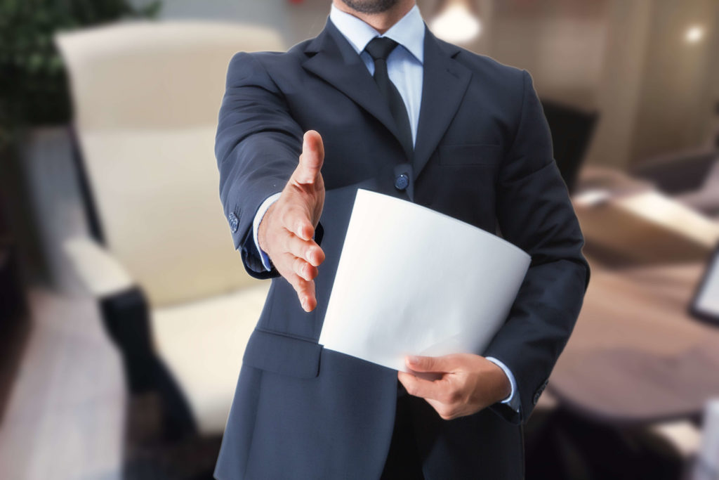 an employee at an employment agency holding out his hand holding a resume