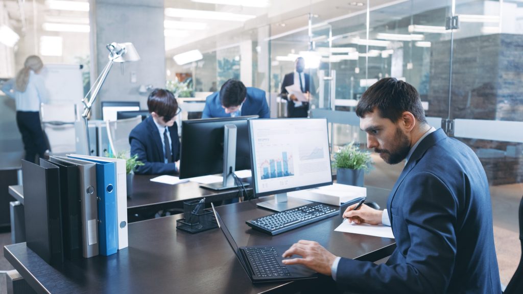 professional-businessman-works-on-his-desktop-computer-uses-laptop-in